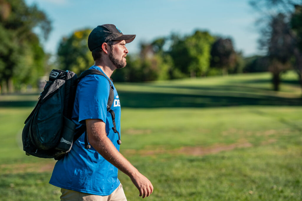 A shot of Brian Earhart from the side as he walks across the course wearing a black AX5 bag.