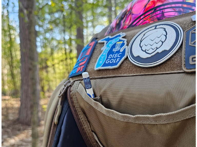 The velcro field on a GRIPeq bag with a variety of patches decorating the bag, as well as a pencil in the pencil holder of the mail compartment flap.