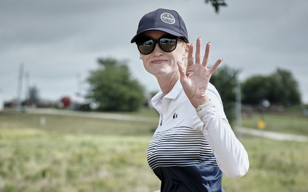 Team GRIPeq member, Holly Finley, waves at the camera as she walks down the fairway.