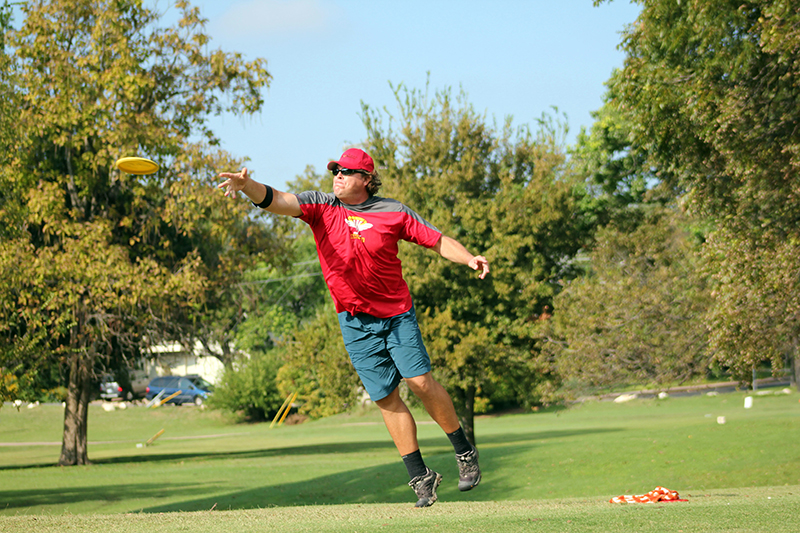 Jay Reading jumping up as he releases a disc golf putt.