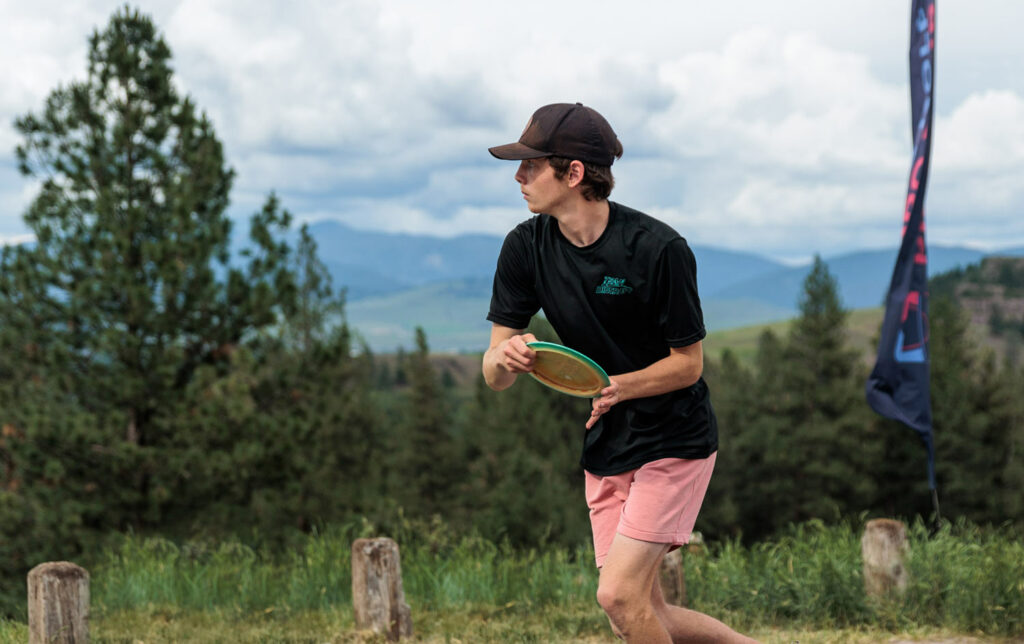 Team GRIPeq member, Evan Scott, gets ready to throw a disc at the Zoo City Open. A mountain range is in the background.