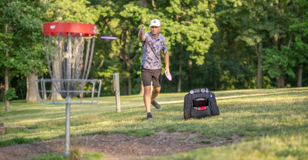 Team GRIPeq member, Adam Hammes, throws in a putt with his bag on the ground next to him.