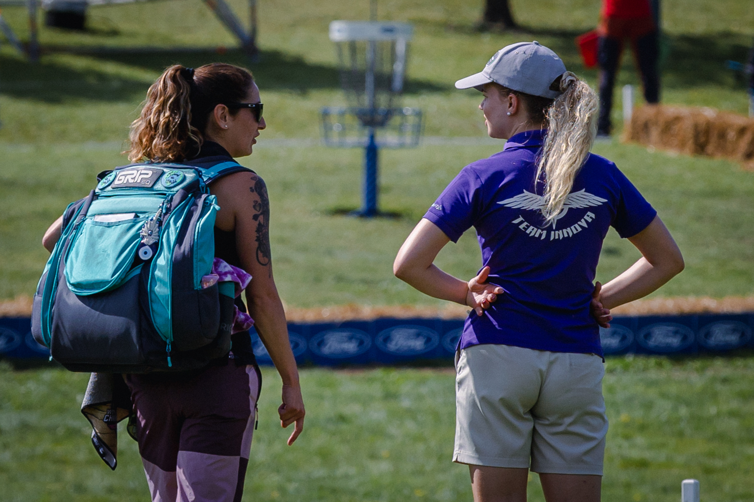 Team GRIPeq member, Jessica Weese, talks with another disc golfer while wearing her GRIPeq bag.