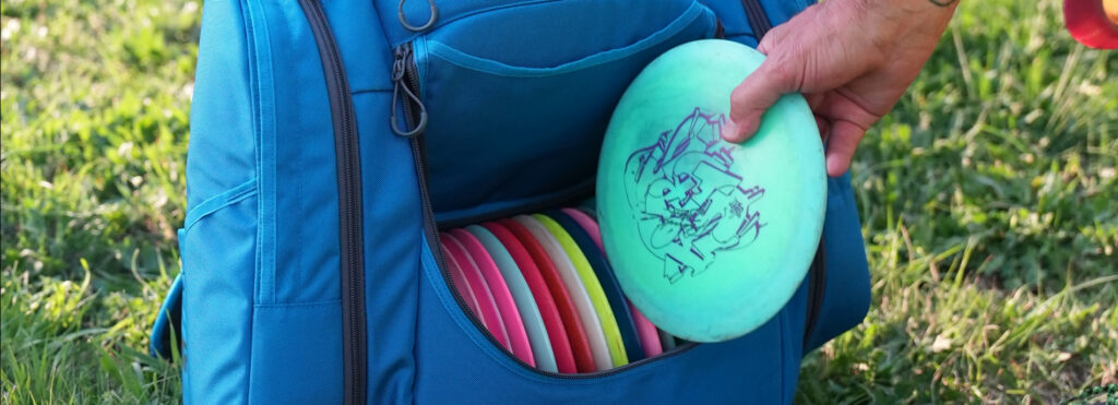 A disc being loaded into a blue GRIPeq AX6 bag. The bag already has a number of discs in it.